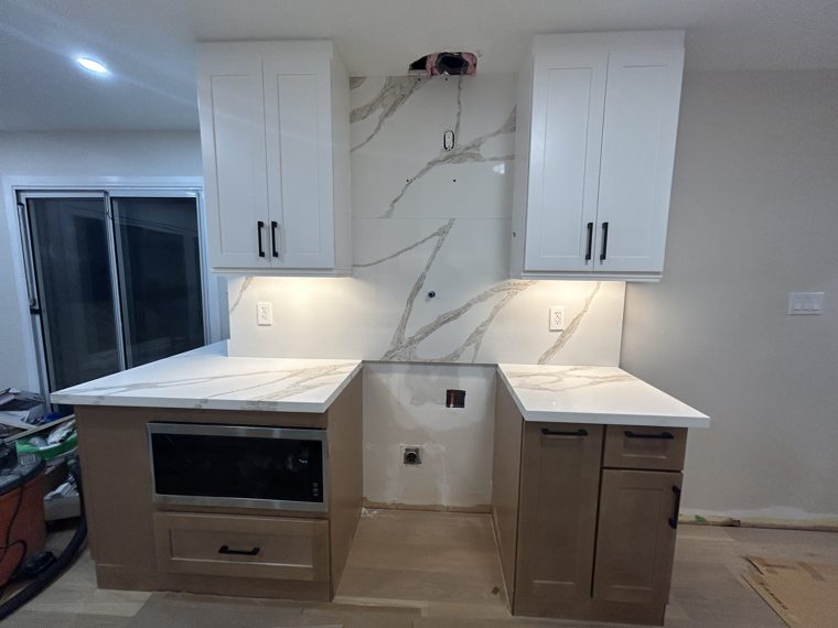 Wood-tone base cabinets and white quartz beside the cooking area