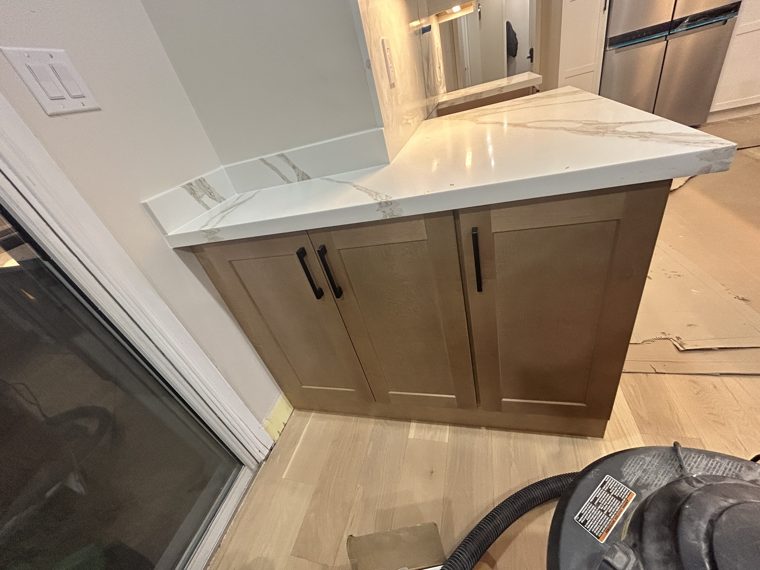 Wood-tone cabinet end panel beneath a quartz countertop