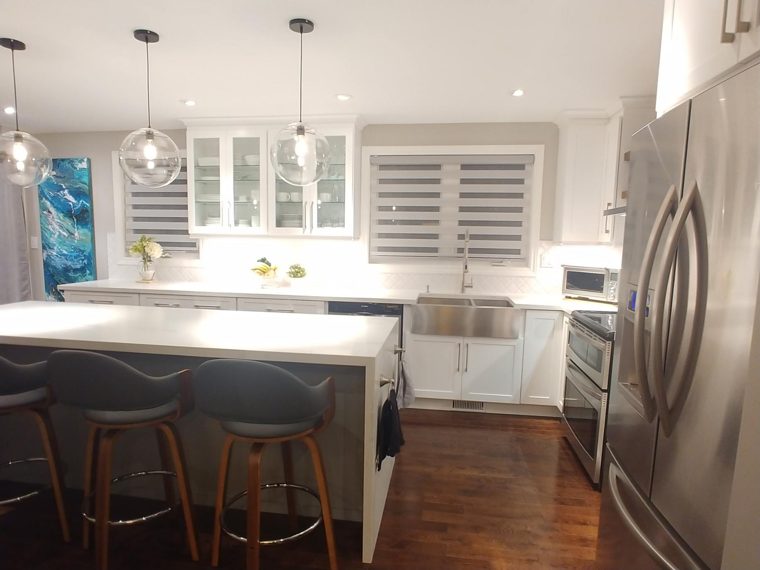 Finished white kitchen with a dark island and pendant lights