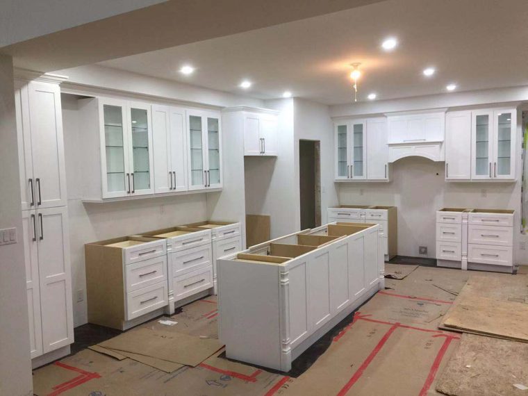White kitchen with glass upper doors and an island being installed