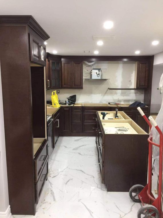 Dark kitchen cabinetry and an island during installation