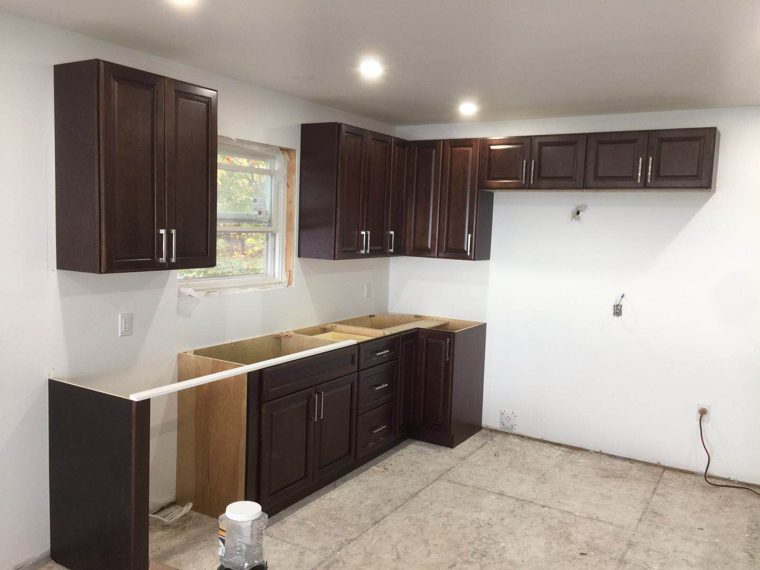 Dark kitchen cabinets fitted along two walls before countertops