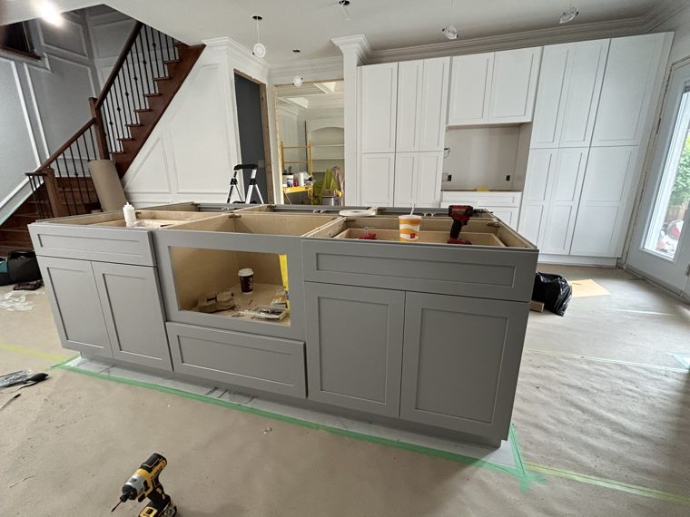 White cabinets and a grey island during installation.